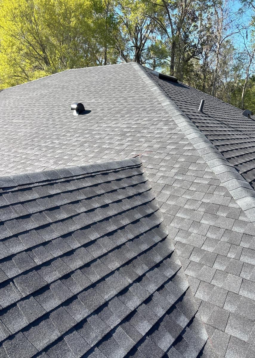 Charcoal gray architectural shingles and capped hips on the new roof of an Alachua home