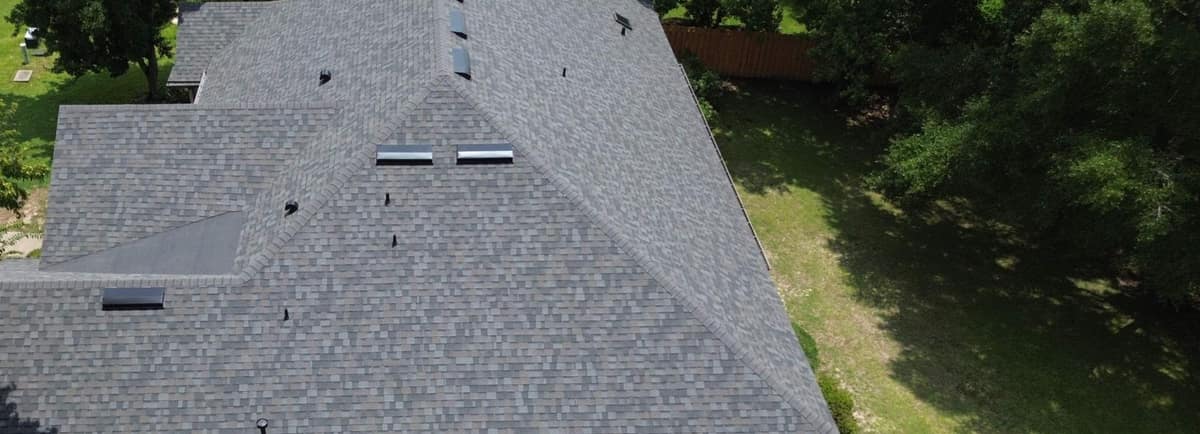 Side of the Alachua roof from the air, with off-ridge vents, capped hips and tall shade trees