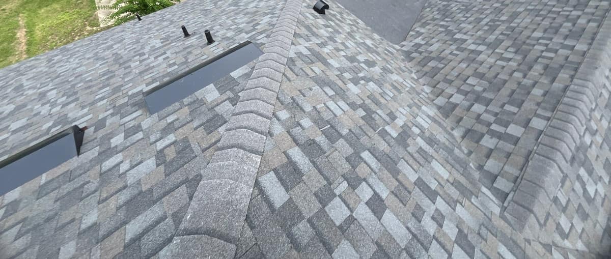 Close view of off-ridge vents, black pipe boots and rounded hip caps on the Alachua roof