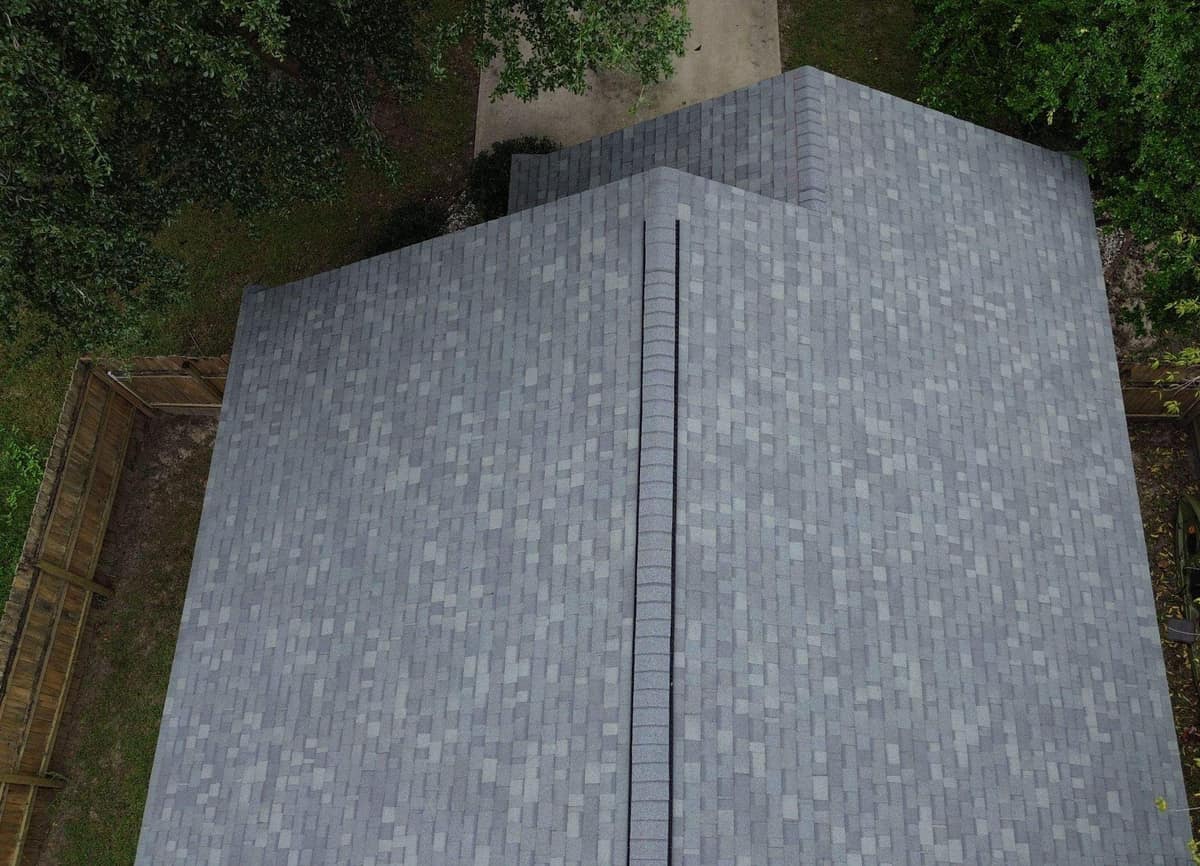 Drone view down the main ridge and ridge vent of a new blue-gray shingle roof in Alachua