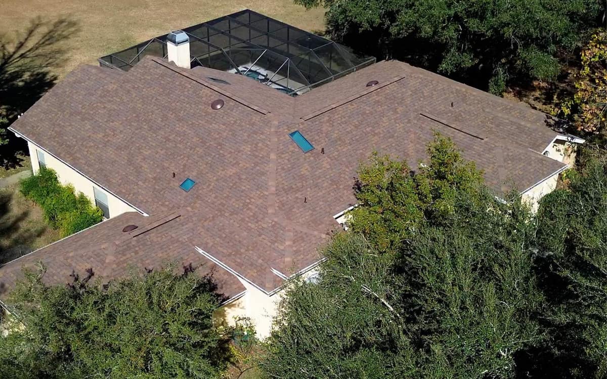 Drone view of the new brown blend shingle roof, skylights and screened pool enclosure on an Alachua home