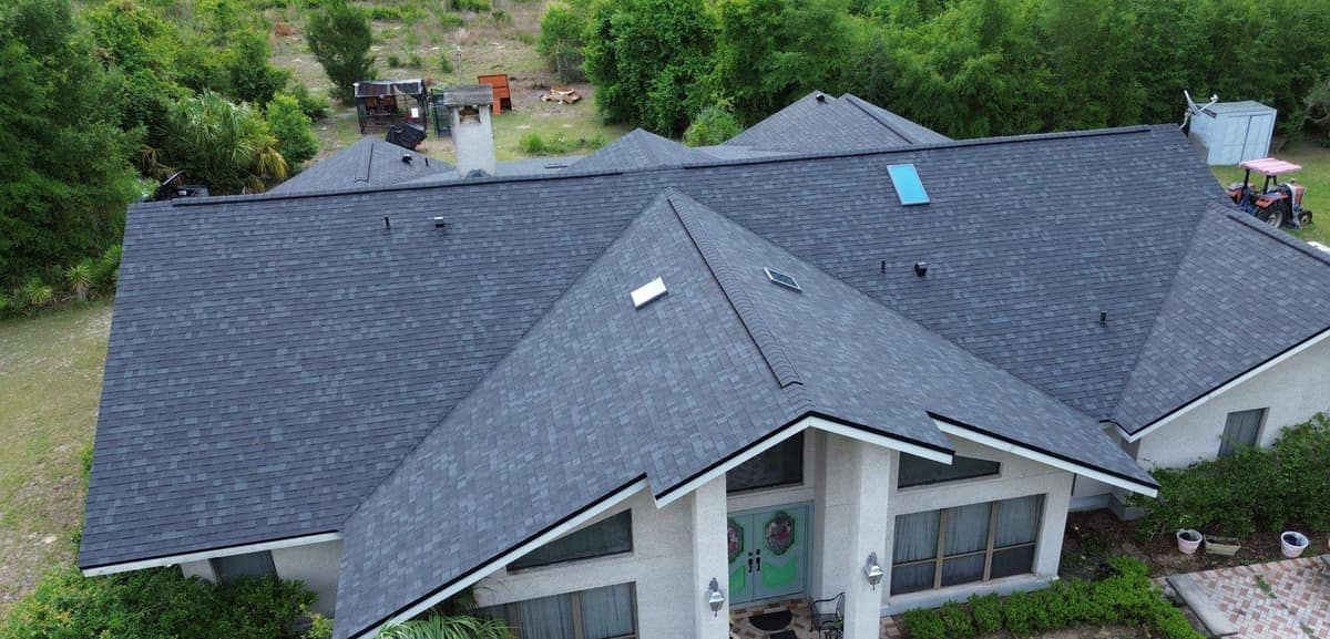 Drone view of an Archer hip roof home with new dark gray shingles over a gabled front entry