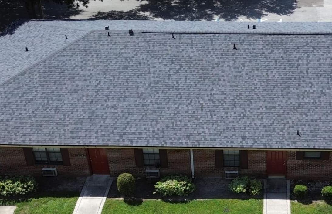 Front of the Gainesville building with red brick, red doors and the new shingle roof above
