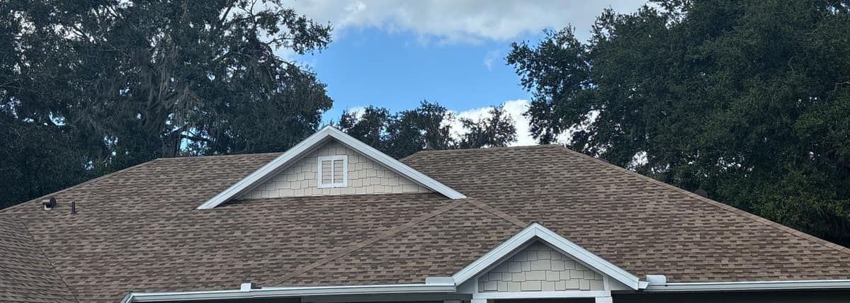New tan architectural shingles on the front of a single-story Gainesville home, with two white-trimmed gables