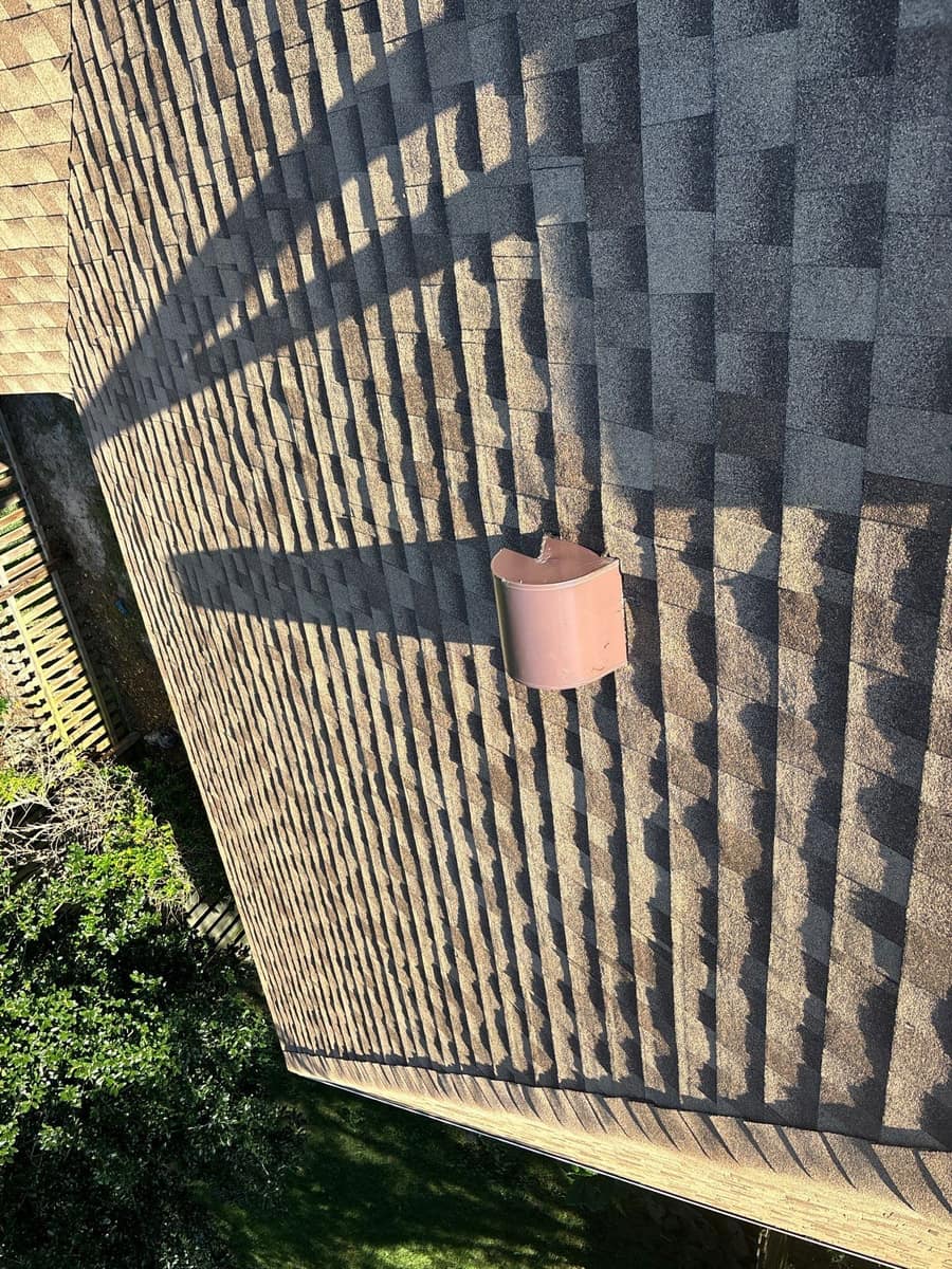 Looking straight down a shaded slope at a rounded brown hood vent and the eave in Gainesville