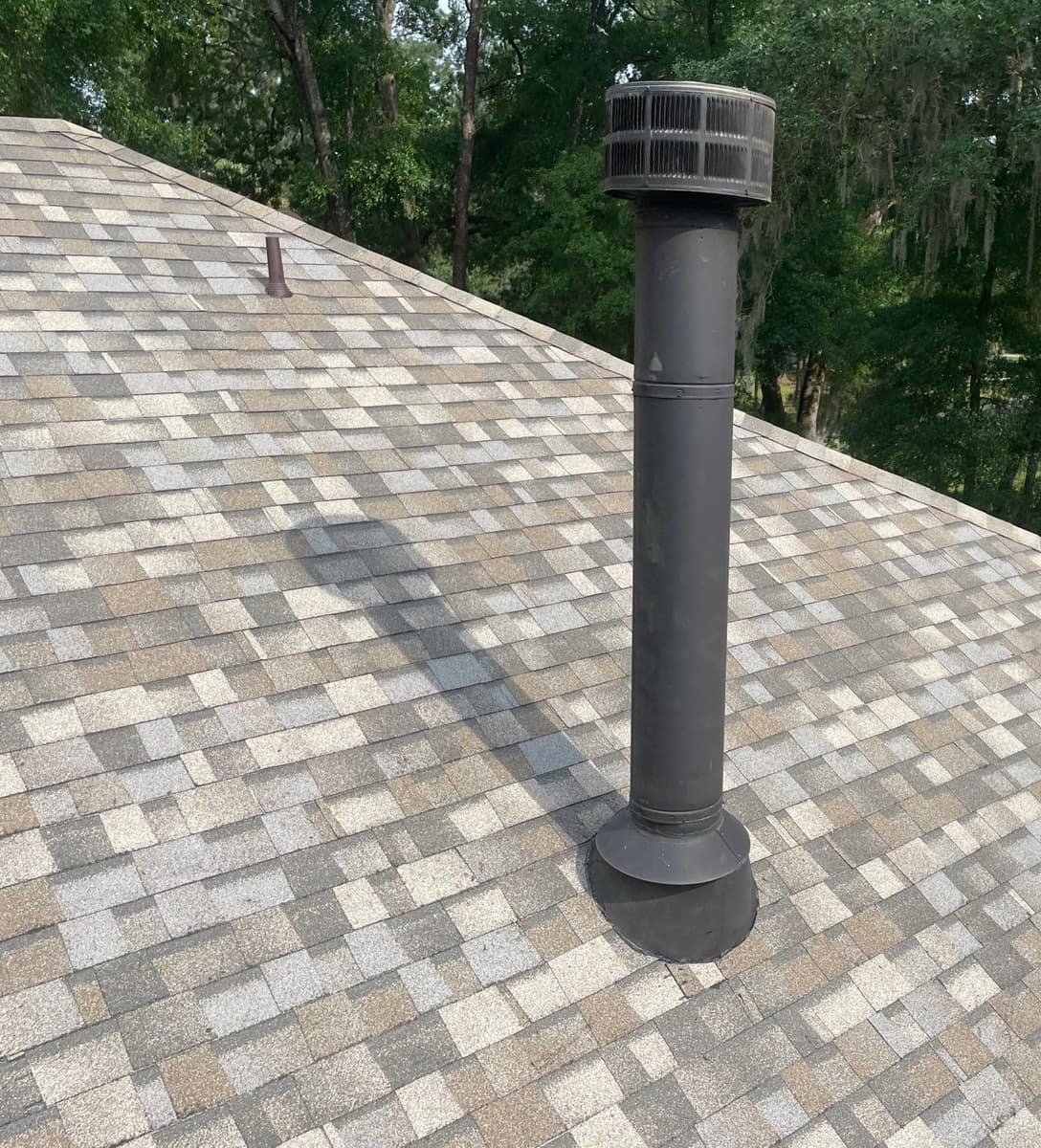 Tall black flue pipe and a small brown vent pipe rising through the new Gainesville shingles