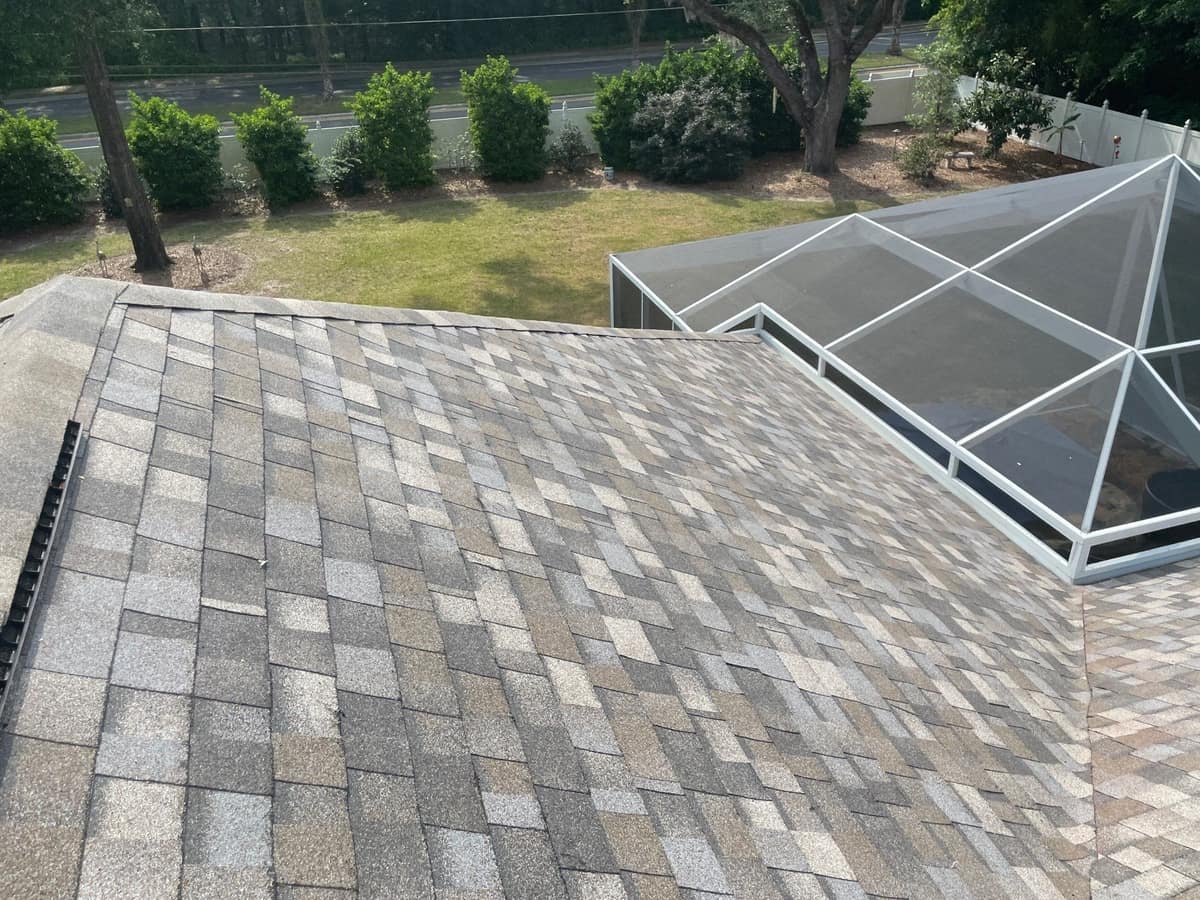 Back of the Gainesville home where the new roof meets a screened enclosure and lawn