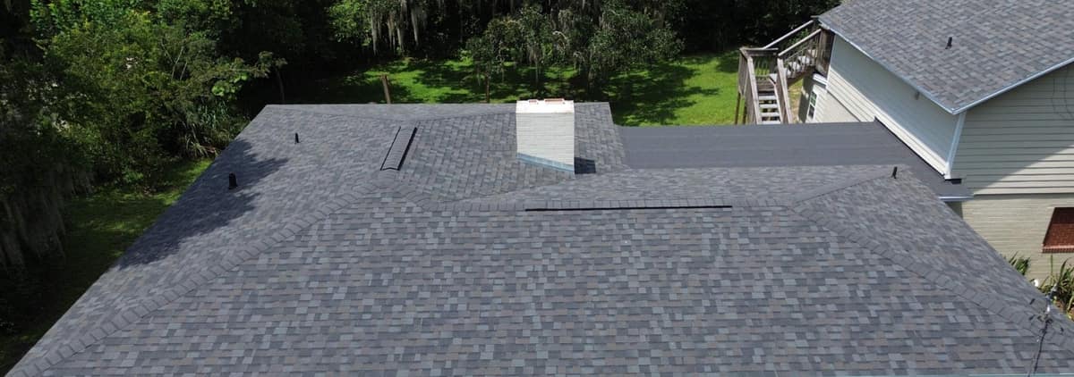 Drone view of the new gray blend hip roof, white chimney and two-story wing in Gainesville