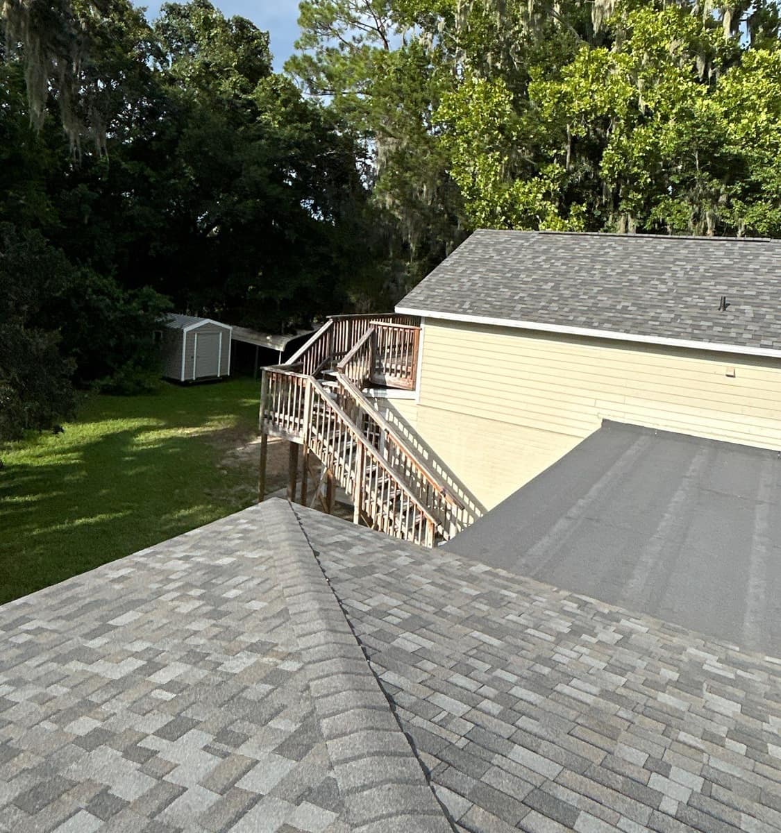 Looking across the low-slope membrane to the deck stair, shed and shaded back yard in Gainesville