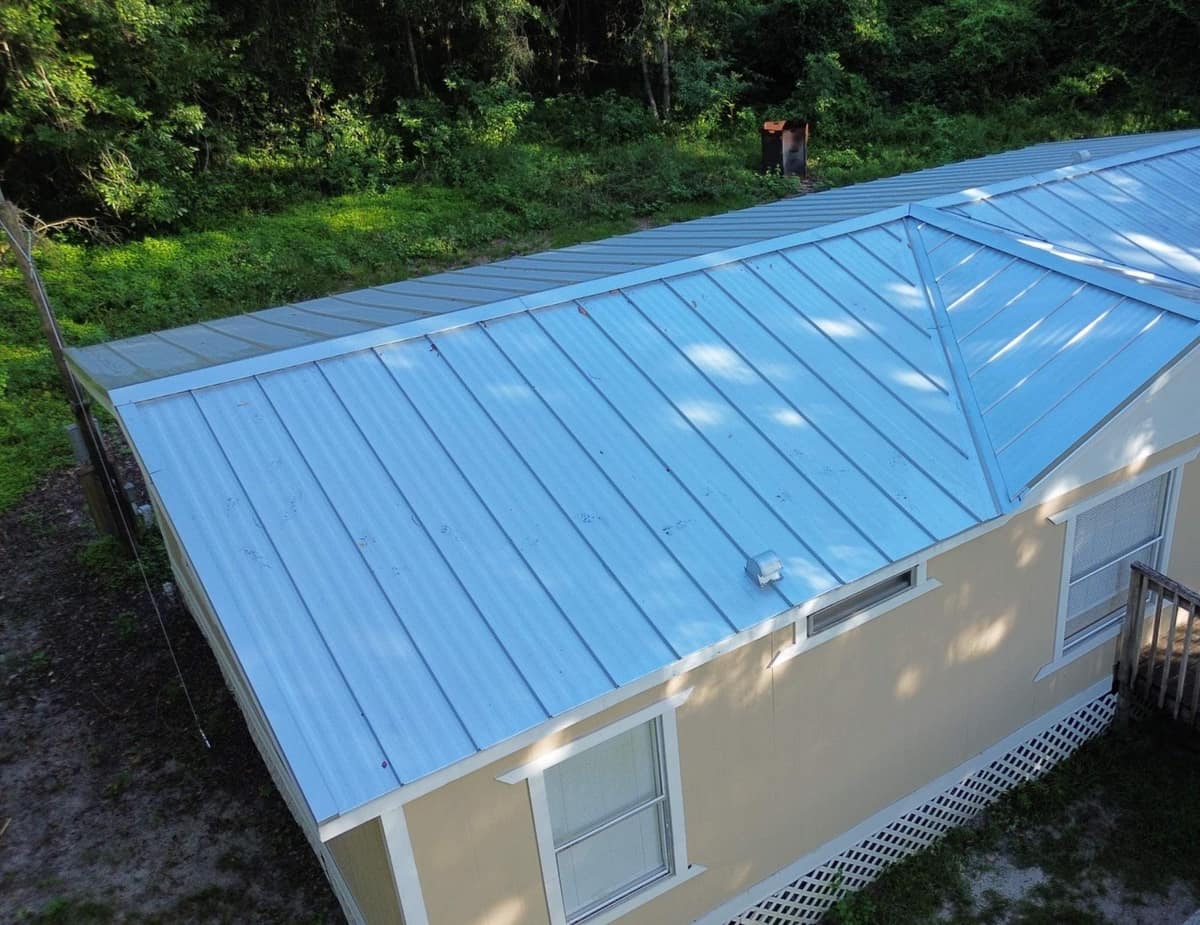 Drone view of a Hampton manufactured home with a new light silver-gray ribbed metal roof