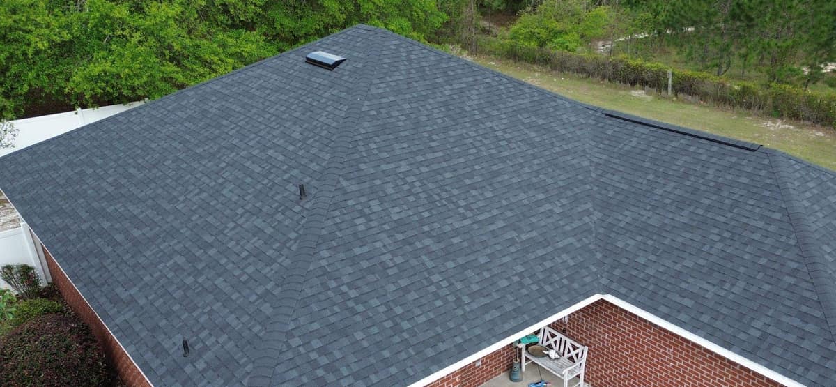 Drone view of a red brick home in Lake City with a new slate gray hip roof