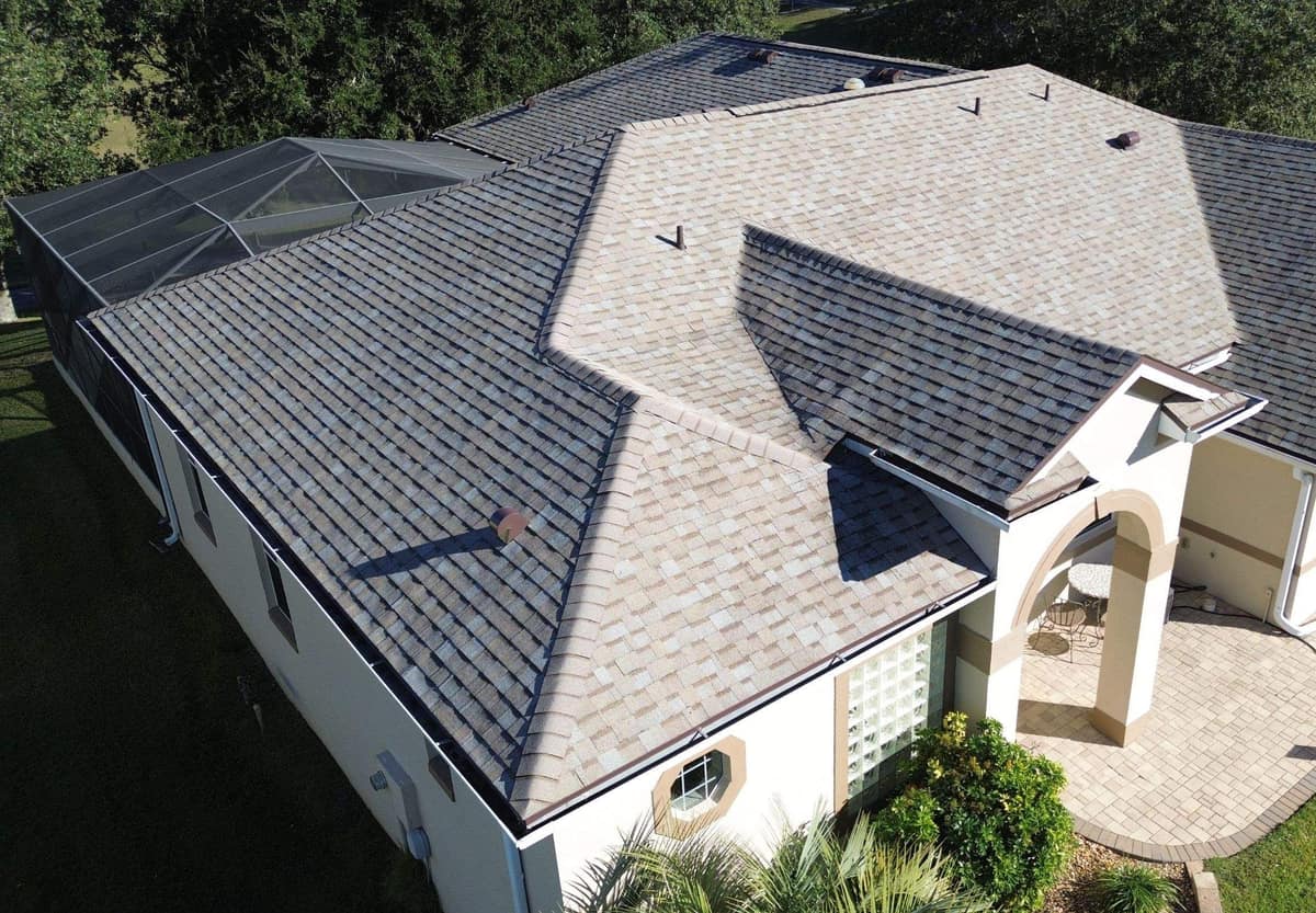 Drone view of a Leesburg stucco home with a new tan and gray shingle hip roof