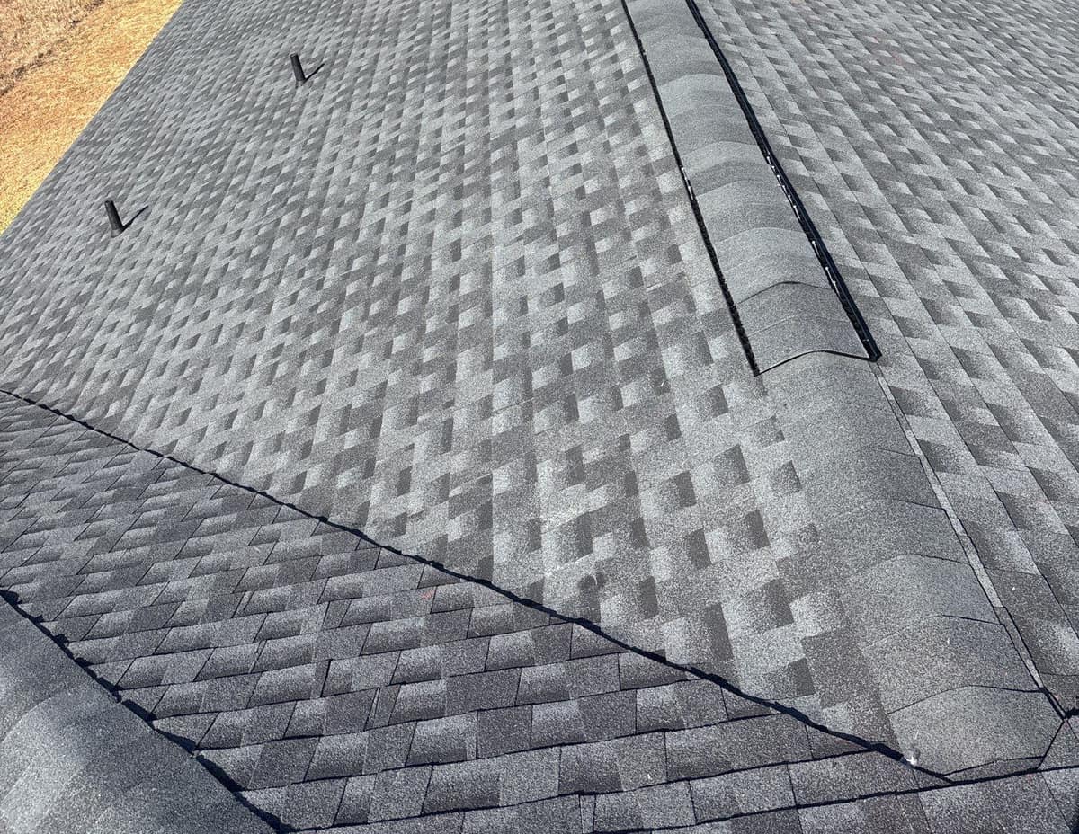 Ridge vent under the cap shingles beside a valley and two vent pipes in Live Oak