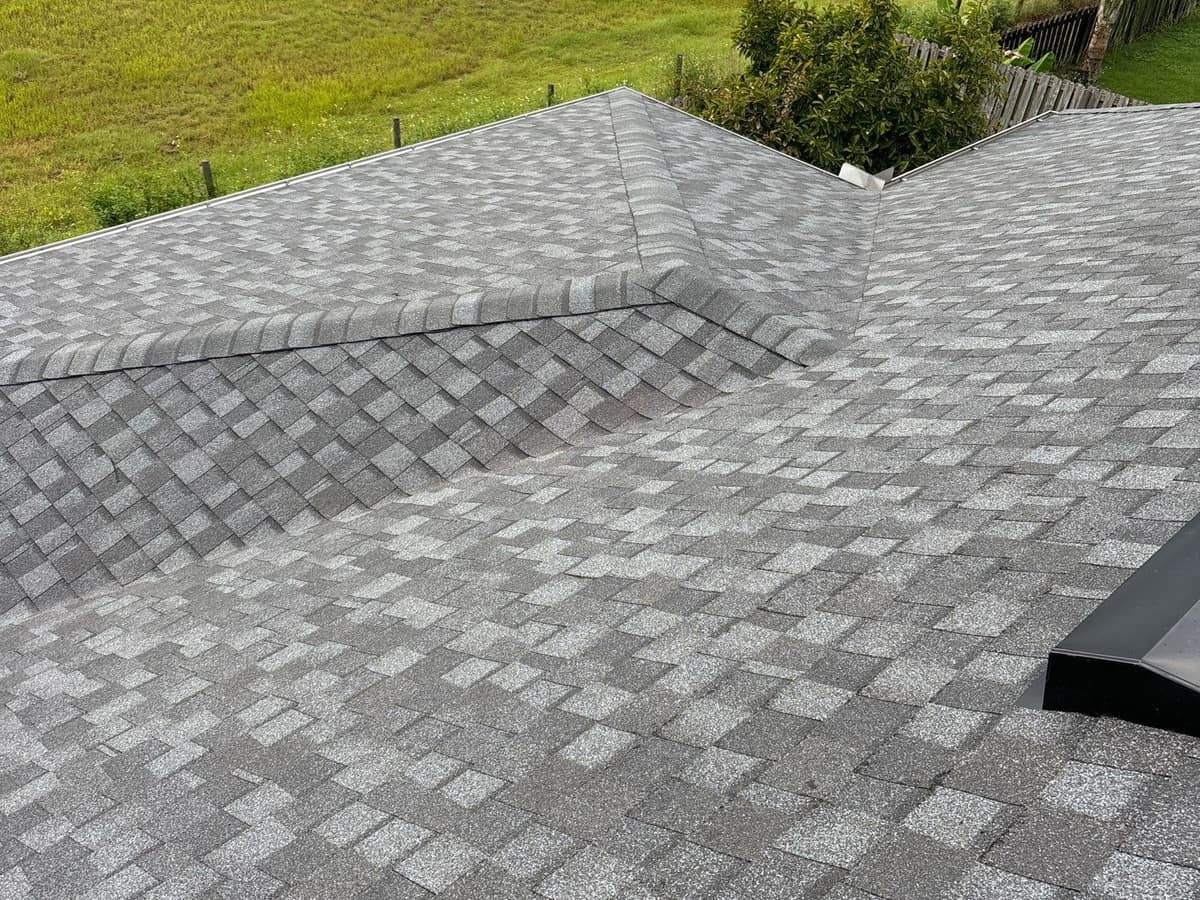 Hipped wing and shingled valley of the new gray roof on a Newberry home backing onto a field