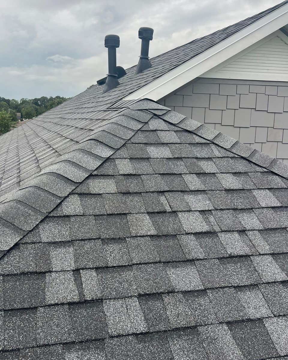 Hip cap shingles climbing to the front gable, with two vent stacks behind, in Newberry