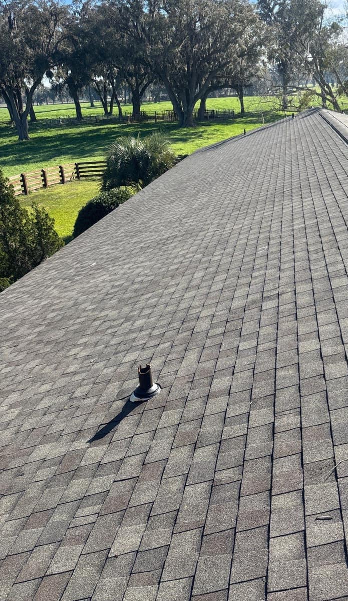 New brown blend shingles running down to the eave above open pasture at a Newberry home