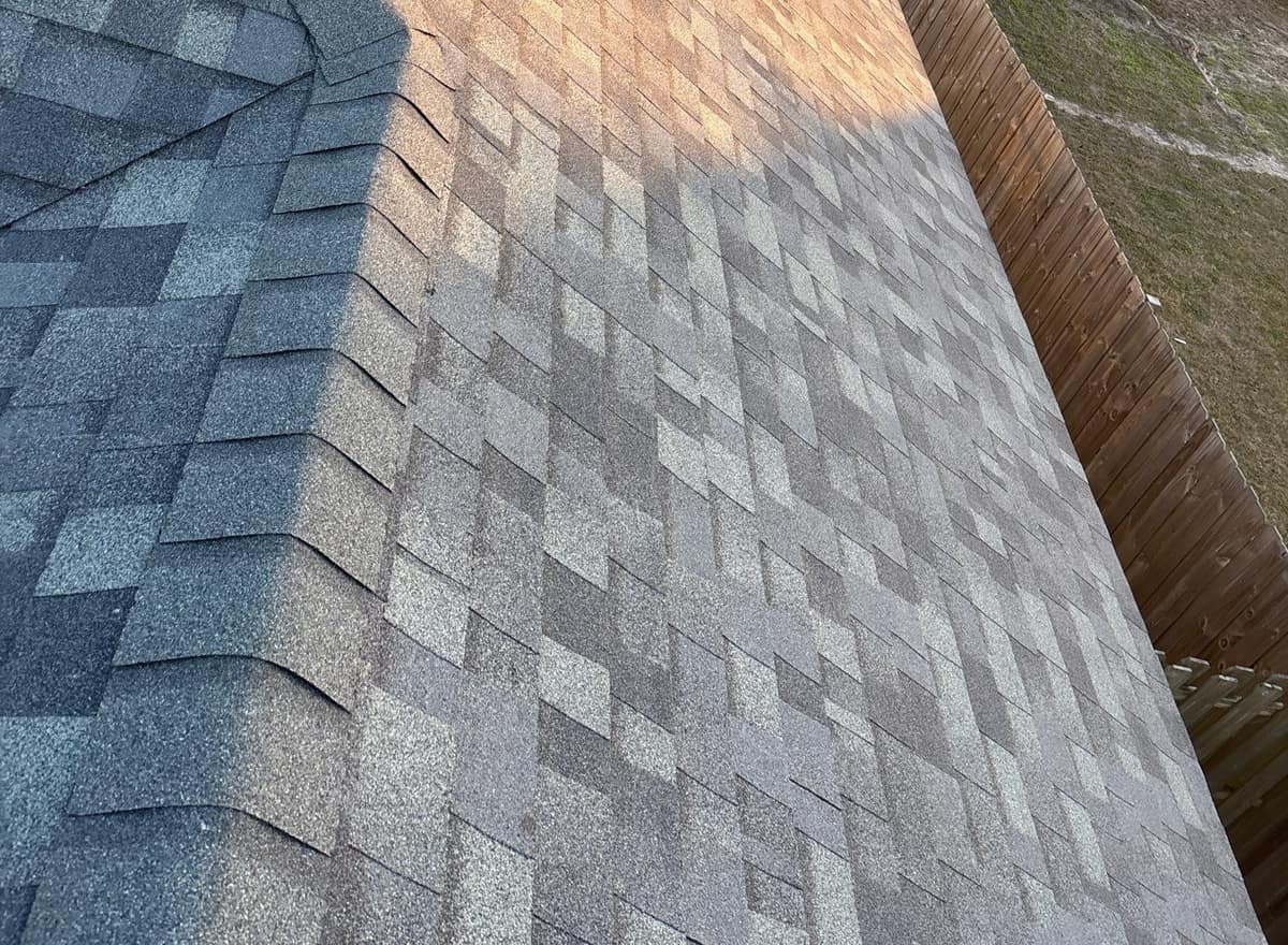 New gray shingle slope with hip caps running out to a wood privacy fence in Newberry
