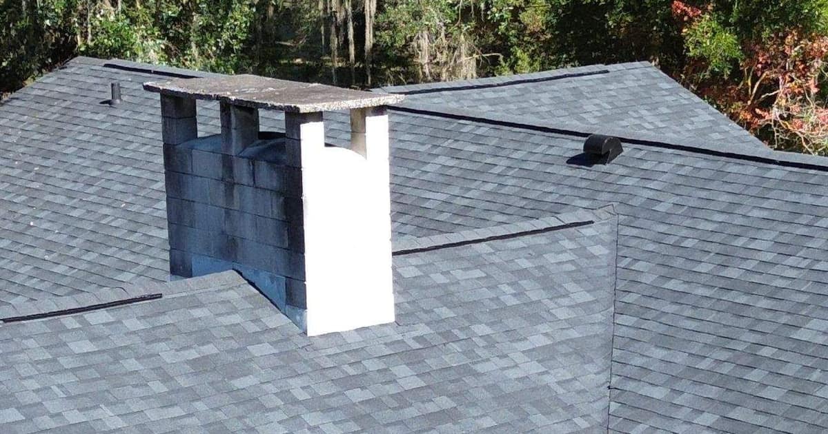 Painted block chimney rising through the new gray shingles on the back of the Newberry house