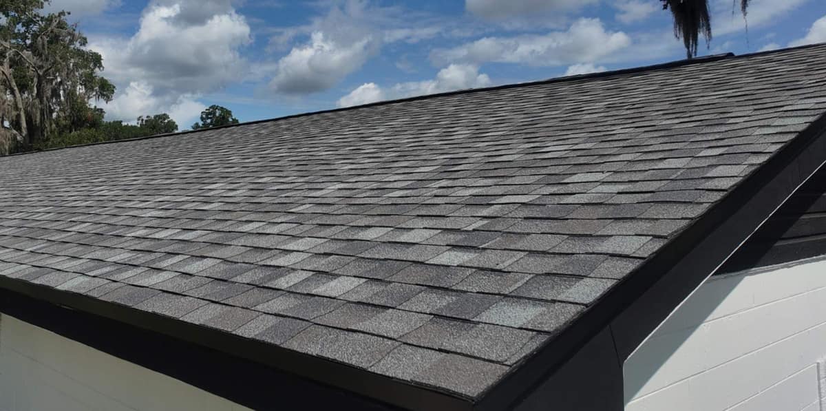 Drone view of the long front slope of the new gray shingle roof on an Ocala ranch home