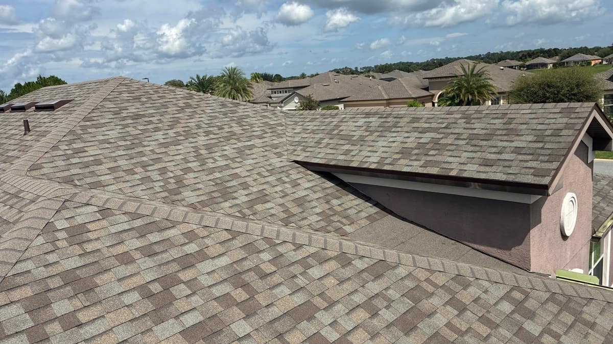 High view across the new shingle roof, its hips and a stucco gable on an Ocala home