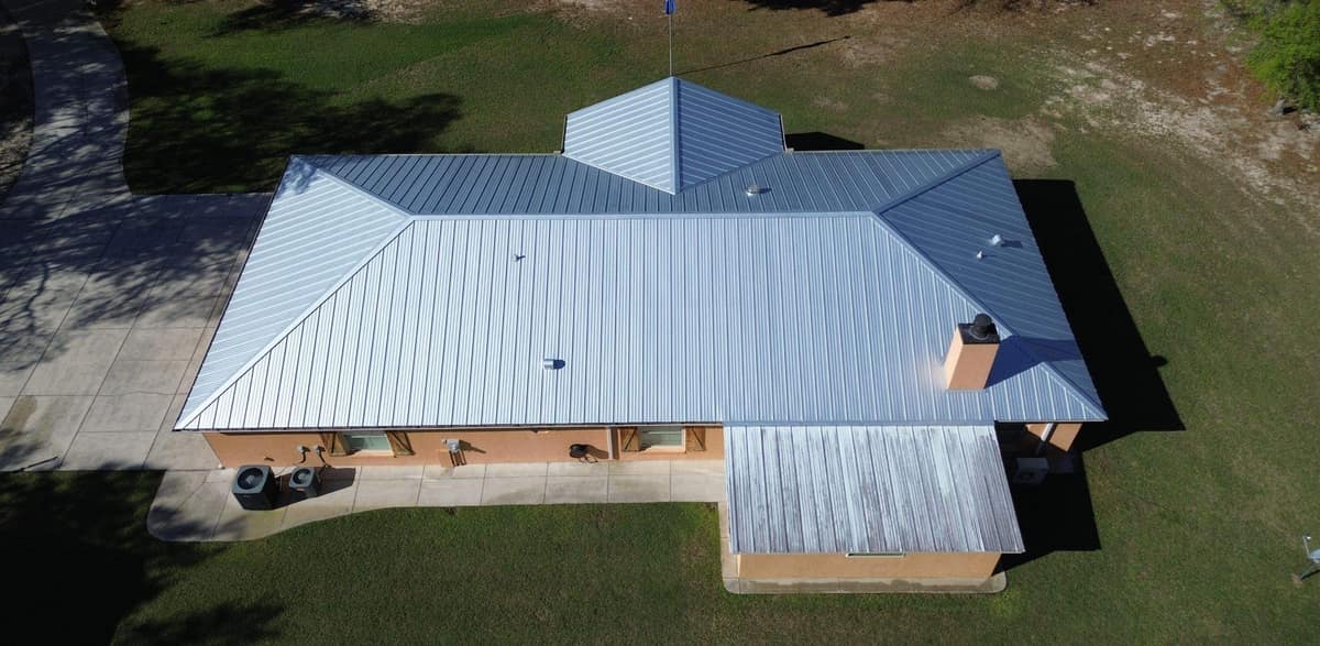 Overhead drone view of a new light silver standing seam metal roof on a Summerfield home