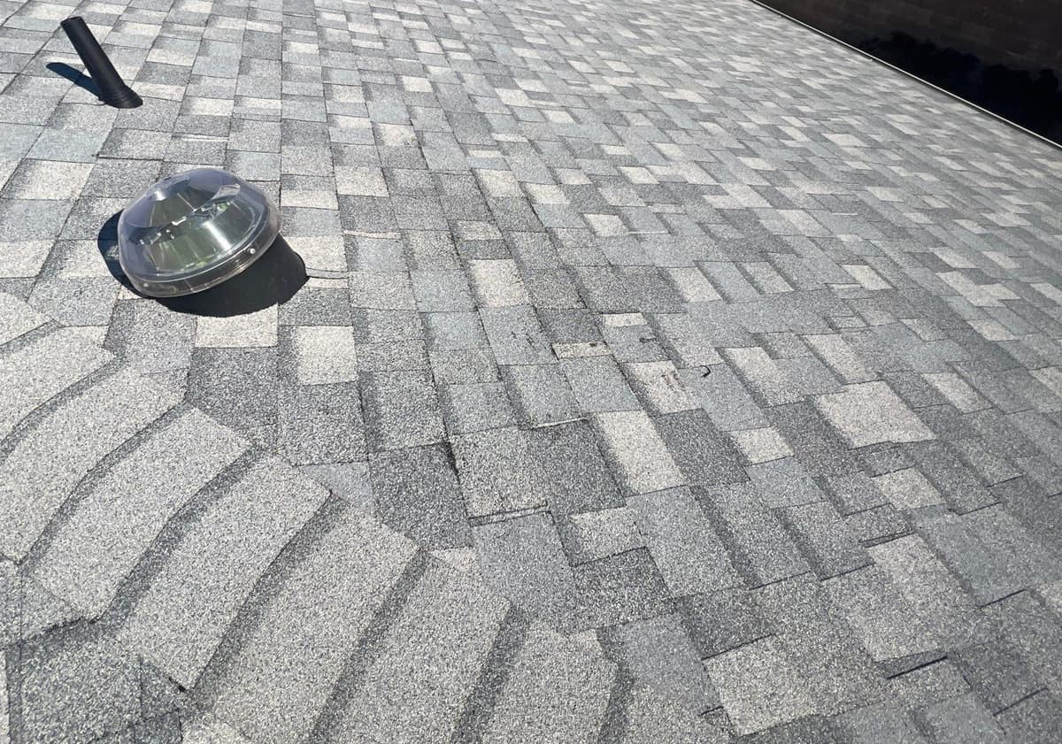 Close view of light gray shingles around a skylight dome and black pipe vent in The Villages