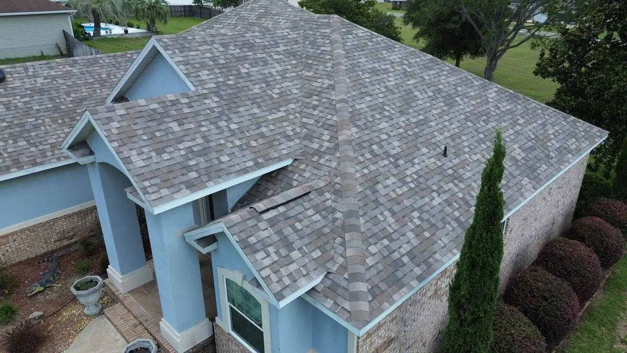 Architectural shingle roof above a blue-and-brick home, elevated front view in Lake City, Florida